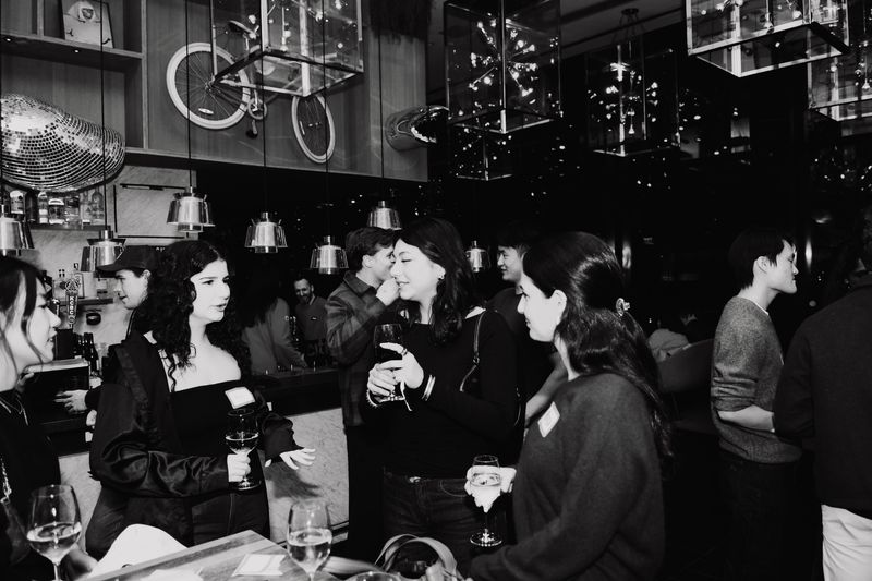 Guests mingling at the bar, in black and white